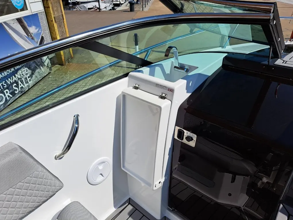 Exterior view of a boat's helm area featuring a sink, storage compartment, and comfortable seating with a scenic backdrop.